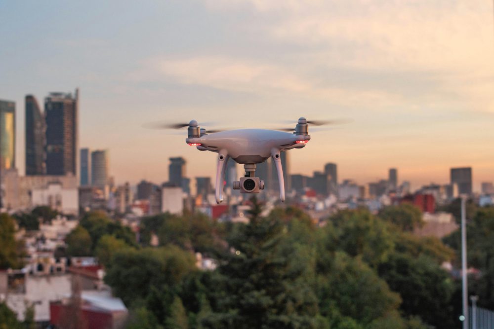 Industrial drone flying over a large cityscape of commercial, residential, institutional, and industrial buildings.